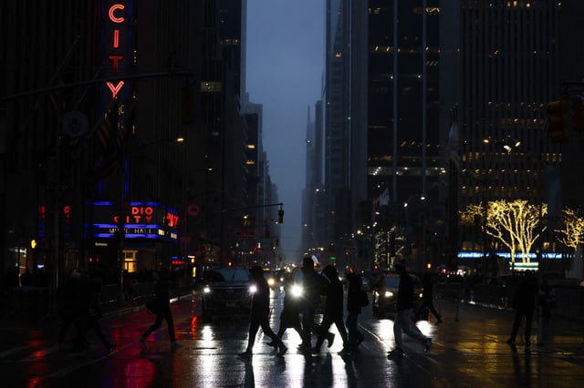 People walk along the Sixth Avenue in Midtown Manhattan as snow falls in New York City on February 15, 2025.