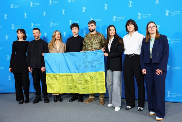 Cast members Olha Bryhynets and Borys Khovriak, Producers Olha Bregman and Natalia Libet, Cinematographer Oleksandr Roshchyn, Editor Nikon Romanchenko and Executive Producer Zoya Lytvyn attend a photo call to promote the documentary film 'Timestamp' as they display a Ukrainian Flag signed by their colleagues who are teachers in Ukraine, at the 75th Berlinale International Film Festival in Berlin, Germany February 20, 2025. REUTERS/Nadja Wohlleben