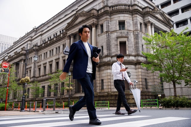 People walk in front of the bank of Japan building in Tokyo, Japan, April 7, 2023. REUTERS/Androniki Christodoulou/File Photo