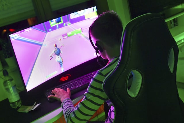 A boy sits and plays the computer game Fortnite on his gaming PC.
