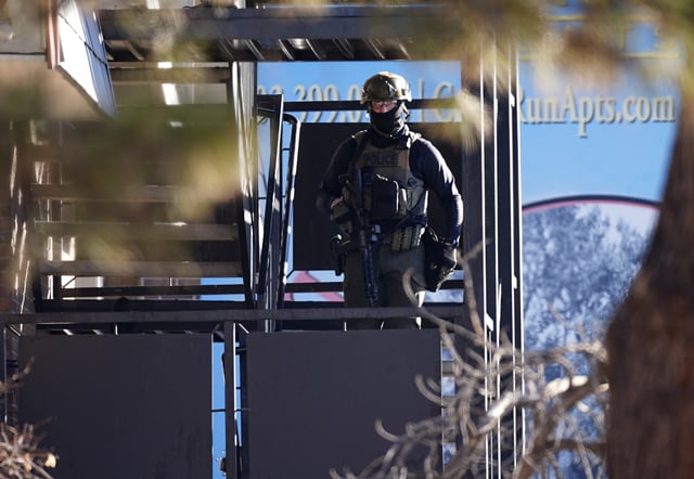 A law enforcement officer stands on a set of stairs outside an apartment complex during a raid Wednesday, Feb. 5, 2025, in east Denver.