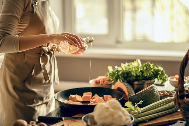Hands of young woman put pumpkin on frying pan for baking in the kitchen. The concept of healthy eating