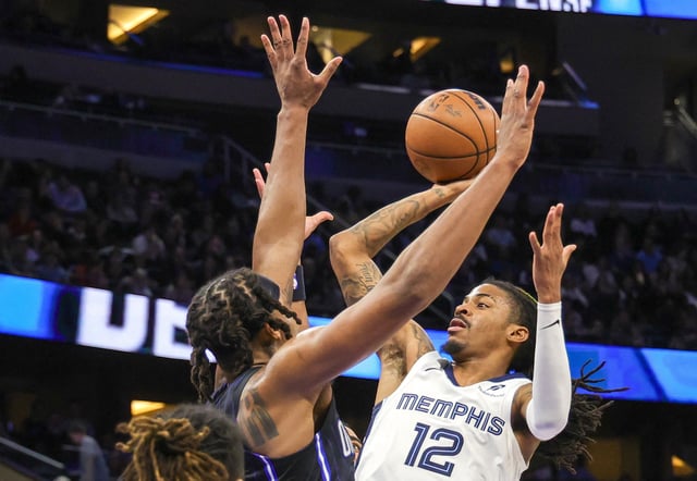 Feb 21, 2025; Orlando, Florida, USA; Memphis Grizzlies guard Ja Morant (12) shoots against Orlando Magic center Wendell Carter Jr. (34) during the second half at Kia Center. Mandatory Credit: Mike Watters-Imagn Images