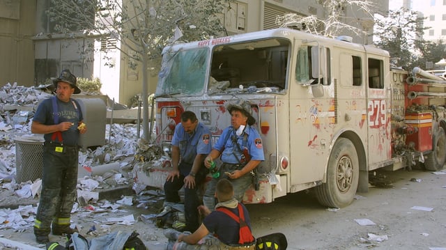 New York City firefighters take a rest at the World Trade Center after two hijacked planes crashed into the Twin Towers September 11, 2001 in New York.
