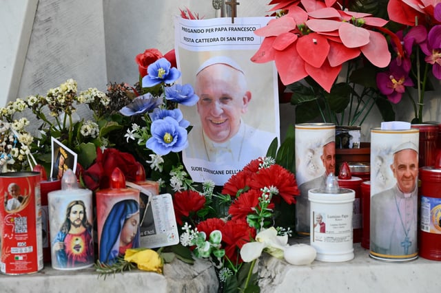 Candles, flowers and a portrait of Pope Francis are laid at the statue of John Paul II outside the Gemelli hospital where Pope Francis is hospitalized in Rome on February 22.