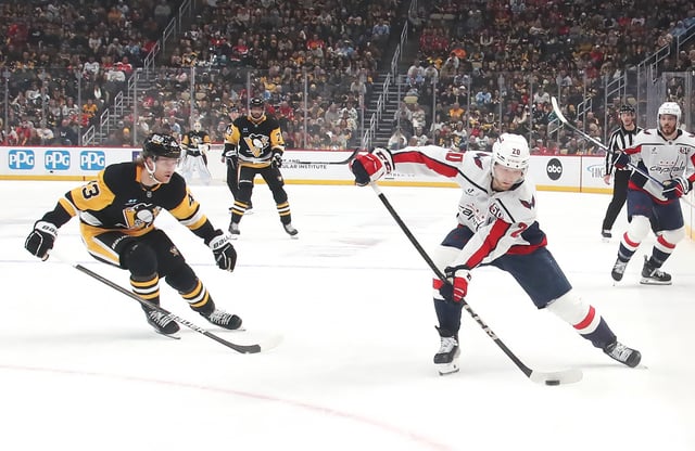 Feb 22, 2025; Pittsburgh, Pennsylvania, USA; Washington Capitals center Lars Eller (20) handles the puck against Pittsburgh Penguins left wing Danton Heinen (43) during the first period at PPG Paints Arena. Mandatory Credit: Charles LeClaire-Imagn Images