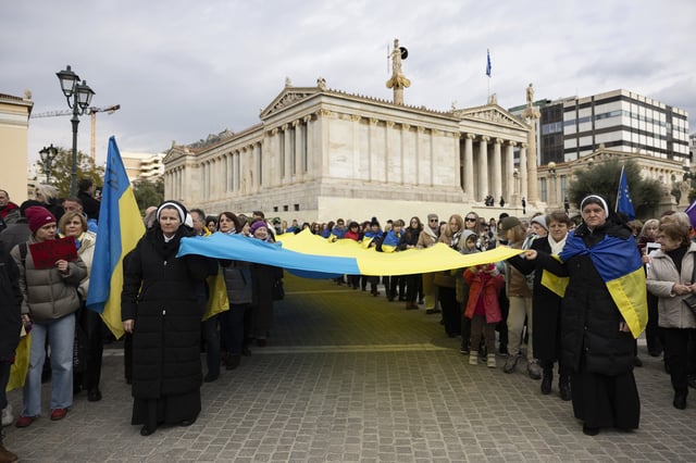 Protesters carry a Ukrainian flag during a rally ahead of the three year anniversary of the Russian invasion of Ukraine, in front of the Athens Academy, Greece, on Sunday, Feb. 23, 2025. (AP Photo/Yorgos Karahalis)