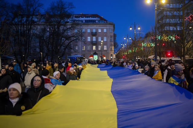 People carry a giant Ukrainian flag to mark the third anniversary of Russia's full-scale invasion of Ukraine, in Vilnius, Lithuania, Sunday, Feb. 23, 2025. (AP Photo/Mindaugas Kulbis)