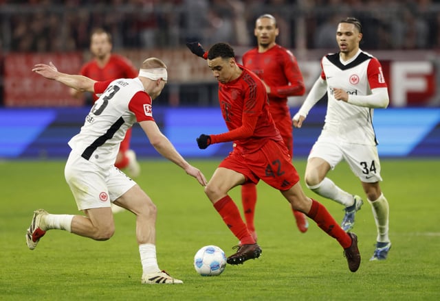 Soccer Football - Bundesliga - Bayern Munich v Eintracht Frankfurt - Allianz Arena, Munich, Germany - February 23, 2025 Bayern Munich's Jamal Musiala in action with Eintracht Frankfurt's Rasmus Kristensen REUTERS/Michaela Stache