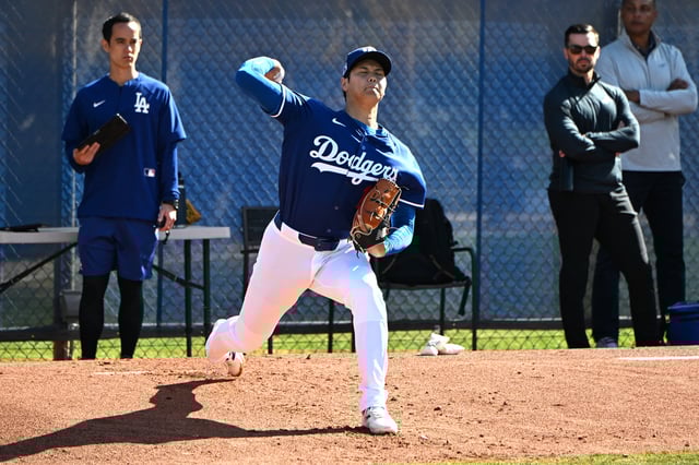 Feb 18, 2025; Glendale, AZ, USA;  Los Angeles Dodgers translator  Will Ireton, left, and Executive Vice President and General Manager Brandon Gomes look on as two-way player Shohei Ohtani (17) throws during a spring training bullpen session at Camelback Ranch. Mandatory Credit: Jayne Kamin-Oncea-Imagn Images/File Photo