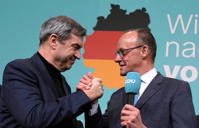 Friedrich Merz, right, leader of the Christian Democratic Union (CDU), and Markus Soeder, leader of the Christian Social Union (CSU), shake hands at the CDU party headquarters in Berlin, Germany, Sunday, Feb. 23, 2025. (Michael Kappeler/dpa via AP)