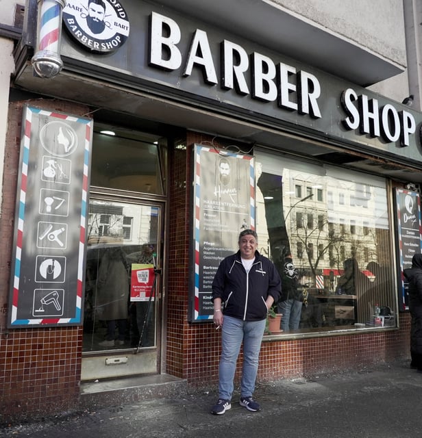 Migrant barber Mohammad Azmouz poses outside a barber shop in the Neukoelln neighbourhood, in Berlin, Germany, February 24, 2025.  REUTERS/Elena Rodriguez