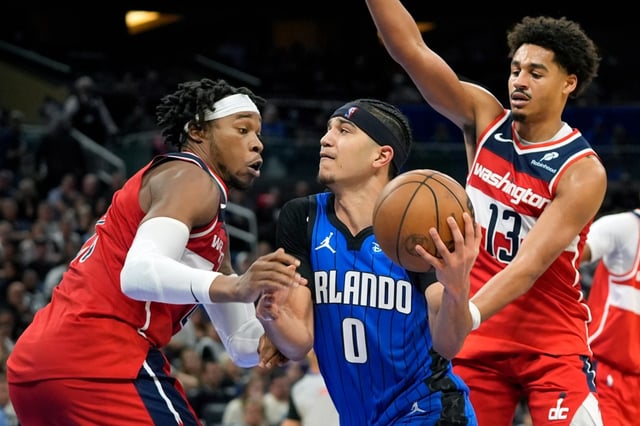 Magic guard Anthony Black (0), who finished with 23 points,  drives to the basket between Washington&#39;s Richaun Holmes, left, and  Jordan Poole (13) during the second half on Sunday night at Kia Center.  (AP Photo/John Raoux)