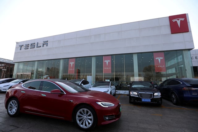 A Tesla car is driven past a store of the electric vehicle maker in Beijing, China, January 4, 2024. REUTERS/Florence Lo/File Photo