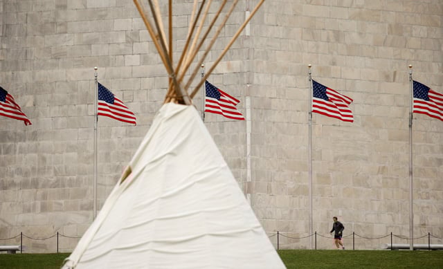 A jogger at the base of the Washington Monument passes a teepee built by members of indigenous tribes to protest the Dakota Access and Keystone XL pipelines in Washington, U.S. March 10, 2017. REUTERS/Kevin Lamarque/File Photo