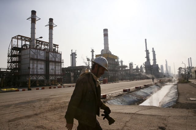 An Iranian oil worker makes his way through Tehran&#39;s oil refinery south of the capital Tehran, Iran, Monday, Dec. 22, 2014.