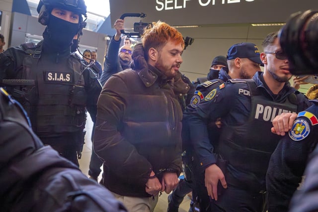 Mohamed Amra, nicknamed ''The Fly", is escorted by armed police officers at the Henri Coanda international airport in Otopeni, Romania, Tuesday, Feb. 25, 2025, before being extradited to France. (AP Photo/Vadim Ghirda)