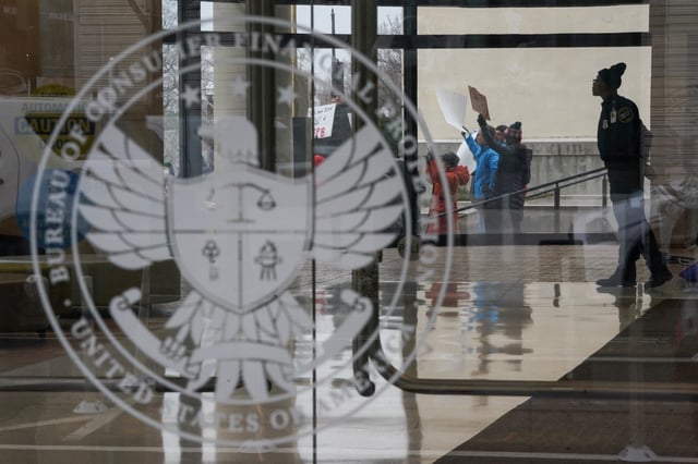 A special police member monitors a protest, while inside the Consumer Financial Protection Bureau (CFPB) building, the day after members of Elon Musk's Department of Government Efficiency (DOGE) moved into the CFPB, in Washington, U.S. February 8, 2025. REUTERS/Nathan Howard