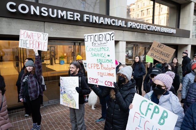 Demonstrators hold signs as they protest against US President Donald Trump and DOGE Elon Musk’s anticipated plan to close the Consumer Financial Protection Bureau in front of the CFPB headquarters in Washington, DC, February 10, 2025. The Trump administration has informed staff at the US consumer protection agency that it is temporarily shuttering its headquarters and pausing all work, according to an email shared on February 10, 2025 with AFP. In the message to staff, Russell Vought, the acting director of the Consumer Financial Protection Bureau, said the CFPB’s Washington office would be closed this week, and told employees not to show up. (Photo by SAUL LOEB / AFP) (Photo by SAUL LOEB/AFP via Getty Images)