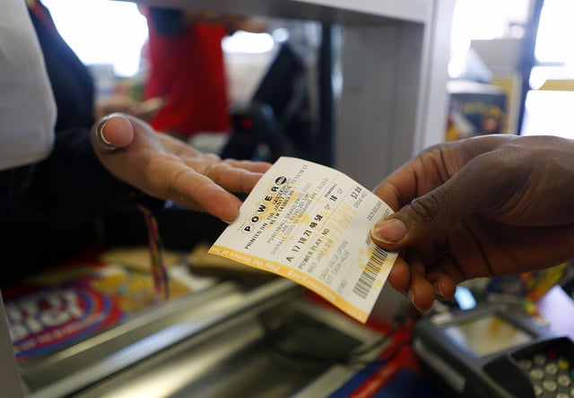 Fabiola Munoz (left) sells another Powerball ticket from the window at the Bonjour Food Store on Yale Street, Tuesday, Jan. 12, 2016, in Houston.