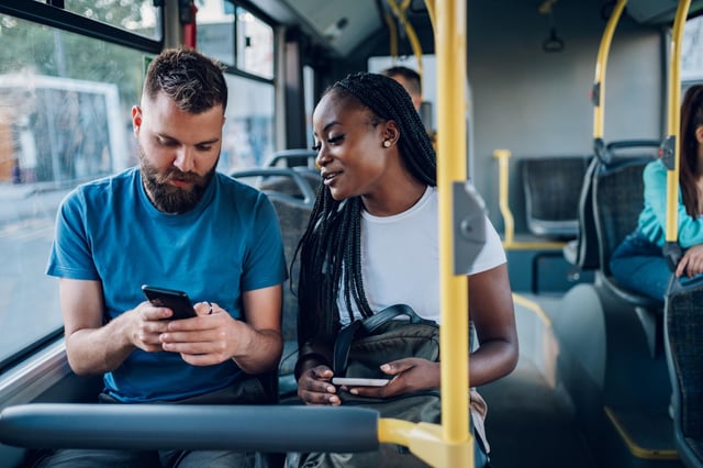 In this stock image, a man and a woman ride together on a bus using their mobile phones.