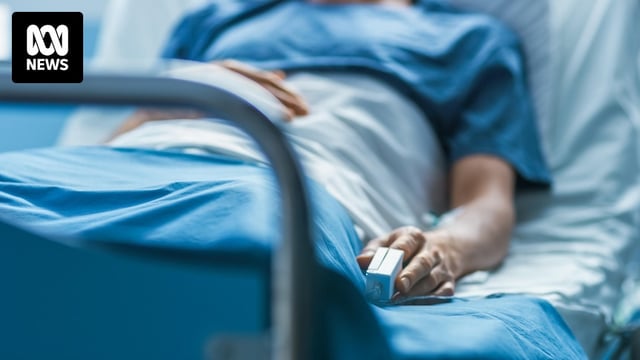 An adult lies in a hospital bed.