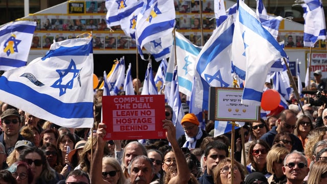 Mourners gather to pay their respects next to a makeshift memorial for the Bibas' at Hostages Square in Tel Aviv on February 26, 2025, on the day of their funeral procession.