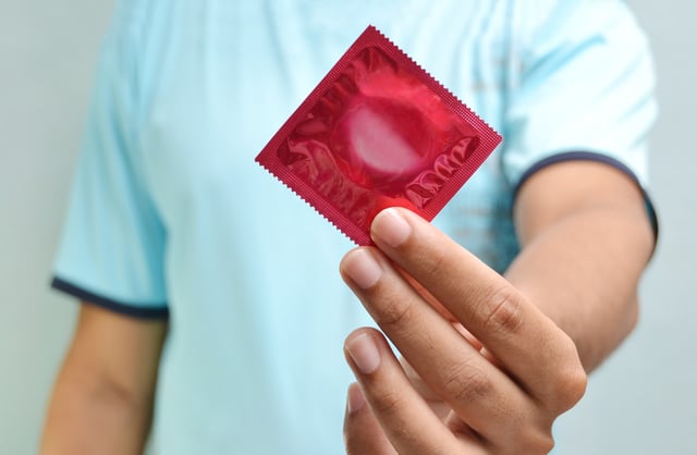 A stock photo of a man holding a condom.