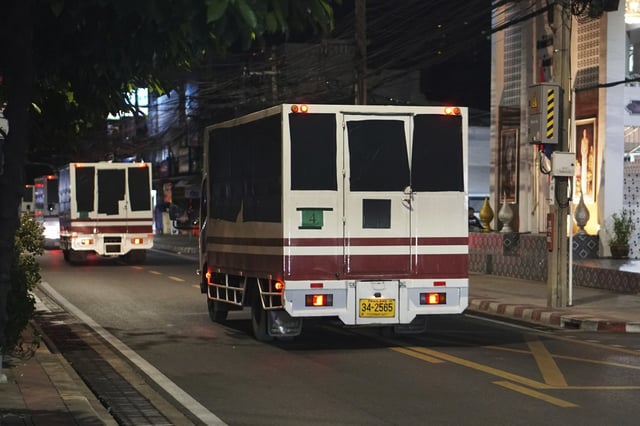 Vehicles with black tape covering the windows leave a detention center in Bangkok on Feb. 27, 2025.