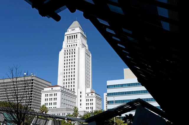 Los Angeles City Hall is framed by the facade in front of the Caltrans building in Los Angeles on Tuesday, May 12, 2015.