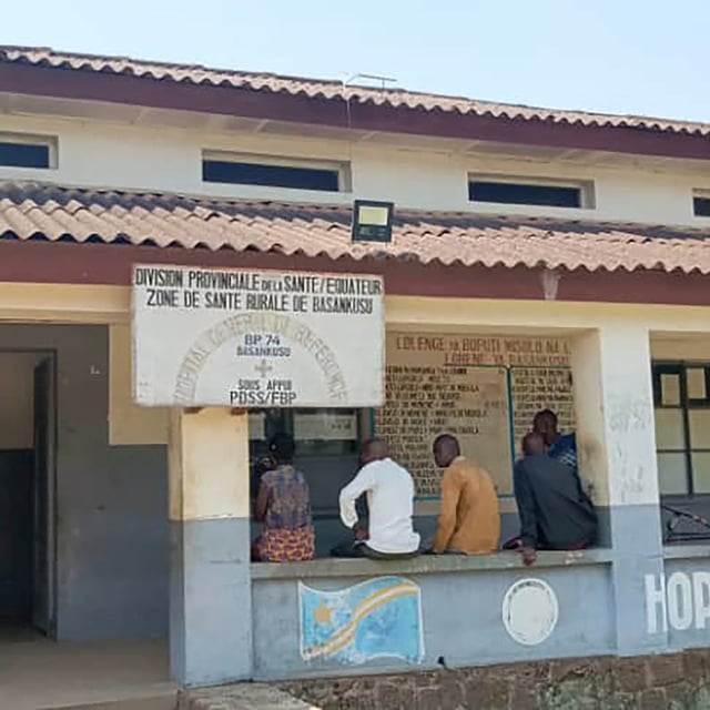 Men sit outside the general hospital in Basankusu, Democratic Republic of the Congo, where some victims of unidentified illnesses are being treated, Thursday, Feb. 27, 2025. (AP Photo/Guy Masele Sanganga)