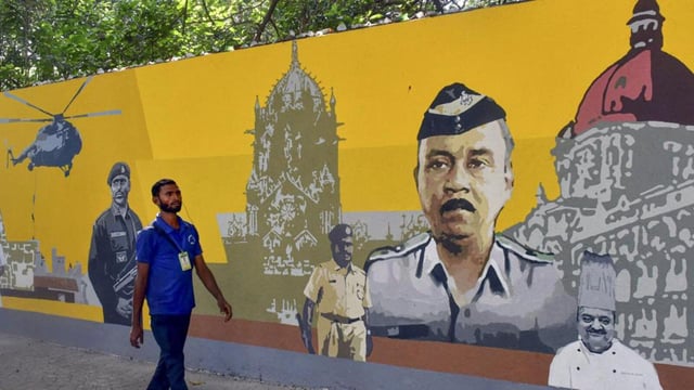 A man walks past a graffiti depicting the 26/11 Mumbai terror attack, at Colaba in Mumbai. (PTI)