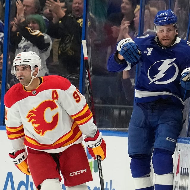 Tampa Bay Lightning defenseman Erik Cernak (81) celebrates behind Calgary Flames center Nazem Kadri (91) after his goal during the third period of an NHL hockey game Thursday, Feb. 27, 2025, in Tampa, Fla. (AP Photo/Chris O'Meara)