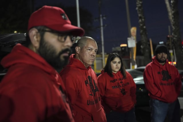 Ron Gochez, second from left, a teacher volunteering with Union del Barrio, an organization advocating for immigrant rights, listens to other volunteers as they gather in a parking lot before searching for ICE activity in Los Angeles Thursday, Feb. 27, 2025. (AP Photo/Jae C. Hong)