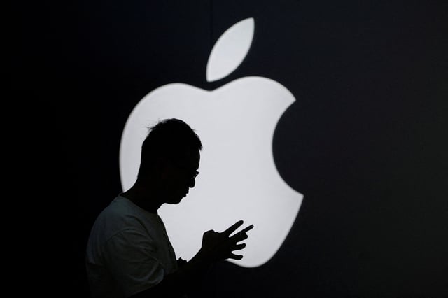 A man check his phone near an Apple logo outside its store in Shanghai, China September 13, 2023. REUTERS/Aly Song/File Photo