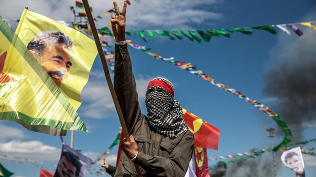 A Kurdish activist surrounded by flags bearing the image of the jailed PKK leader Abdullah Ocalan, who has called on the group to disarm