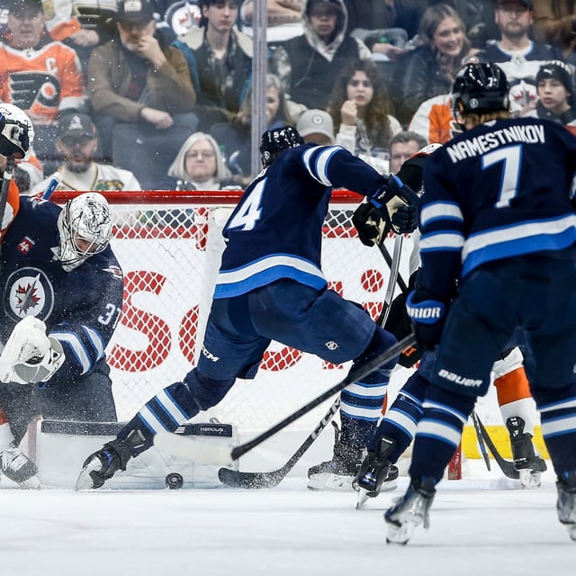Winnipeg Jets goaltender Connor Hellebuyck (37) saves the shot as Dylan Samberg (54) defends against the Philadelphia Flyers during second period NHL action in Winnipeg on Saturday, March 1, 2025. THE CANADIAN PRESS/John Woods