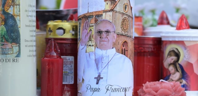 Des bougies déposées au pied de la statue de Jean-Paul II devant l'hôpital Gemelli à Rome où est hospitalisé le pape François, le 2 mars 2025