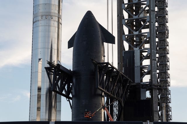 The Super Heavy booster (left) is seen alongside the Starship spacecraft, or upper stage (right), which is secured in the arms of the "Mechazilla" launch tower at the Starbase facility near Brownsville, Texas, on Sunday.