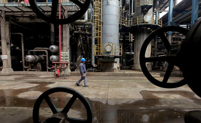 A worker walks past oil pipes at a refinery in Wuhan, Hubei province March 23, 2012. REUTERS/Stringer//File Photo