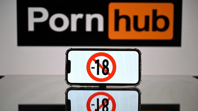 This photograph taken on May 24, 2022 in Toulouse shows screens displaying a minor child sign and the logo of the pornographic site Pornhub. 