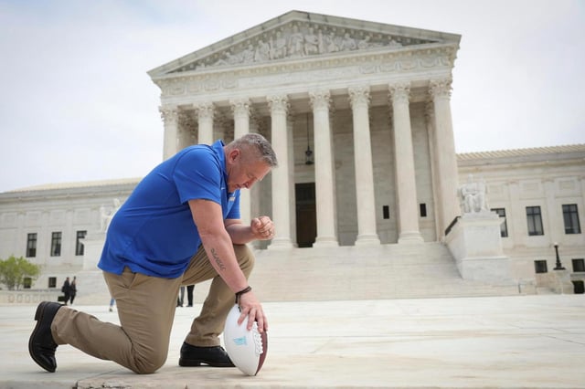In this photo from April 25, 2022, former Bremerton High School assistant football coach Joe Kennedy takes a knee in front of the U.S. Supreme Court after his legal case, Kennedy vs. Bremerton School District, was argued before the court in Washington, DC. Kennedy was terminated from his job by Bremerton public school officials in 2015 after refusing to stop his… (Win McNamee/Getty Images North America/TNS)