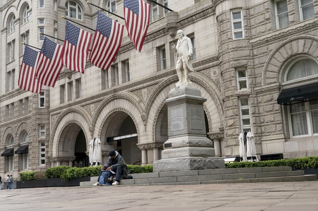 FILE - A man sits by Old Post Office building, May 12, 2022, in Washington. (AP Photo/Gemunu Amarasinghe)