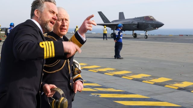 The King and Captain Will Blackett watch F-35B warplanes landing on HMS Prince of Wales