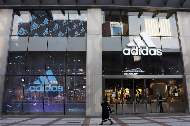 A woman walks past a store of sporting goods retailer Adidas at a shopping mall in Beijing, China March 25, 2021. REUTERS/Florence Lo/File Photo
