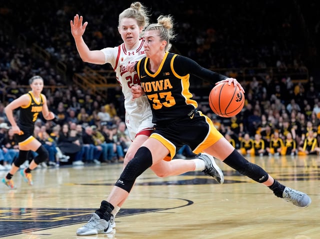 Iowa guard Lucy Olsen drives to the lane as Wisconsin guard Natalie Leuzinger defends during a Big Ten conference game.