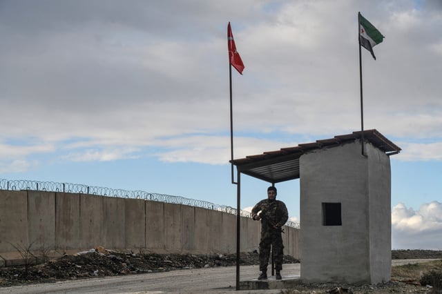 Un membre de l’Armée syrienne libre soutenue par la Turquie en poste long du mur à la frontière nord avec la Turquie, le 18 décembre 2021.