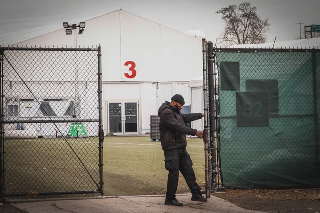 A worker closes a gate at the Randall's Island migrant shelter.