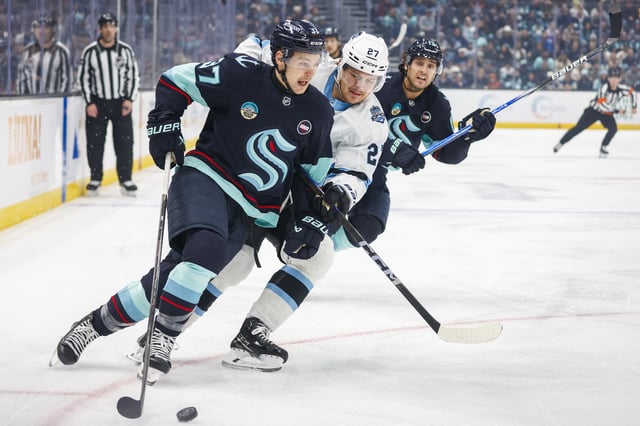 Dec 30, 2024; Seattle, Washington, USA; Seattle Kraken center Yanni Gourde (37) skates with the puck ahead of Utah Hockey Club center Barrett Hayton (27) during the first period at Climate Pledge Arena. Mandatory Credit: Joe Nicholson-Imagn Images/File Photo