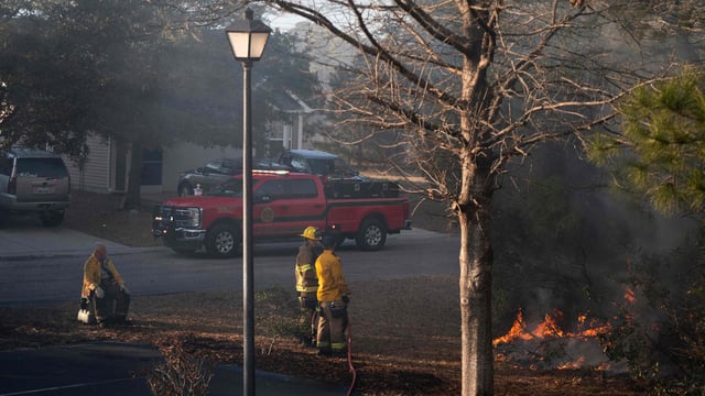 Firefighters attend to a flare-up in the Carolina Forest neighborhood on March 2, 2025 in Myrtle Beach, South Carolina. 